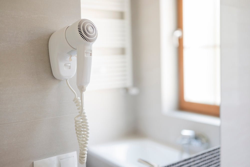 A modern residential bathroom featuring a wall-mounted hand dryer for sanitary home use.