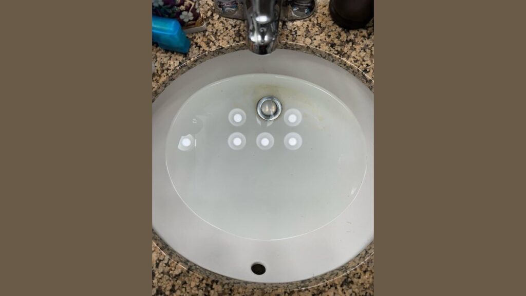 A bathroom sink overflowing with water due to a plumbing issue.