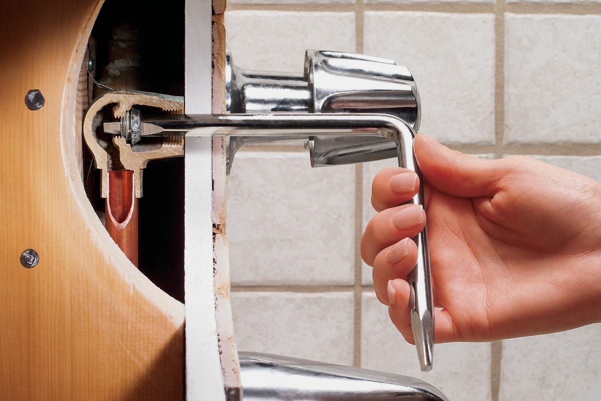 Hands adjusting the temperature gear on a bathtub faucet cartridge during a repair.