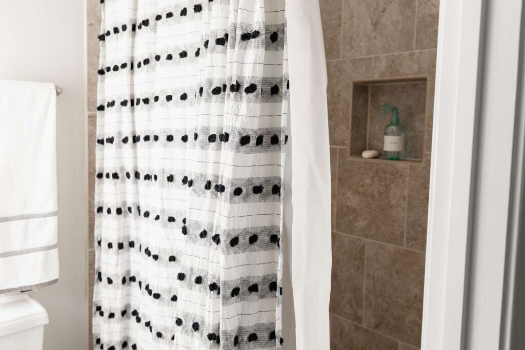 A clean shower curtain hangs in a bright bathroom, demonstrating effective mold removal techniques.