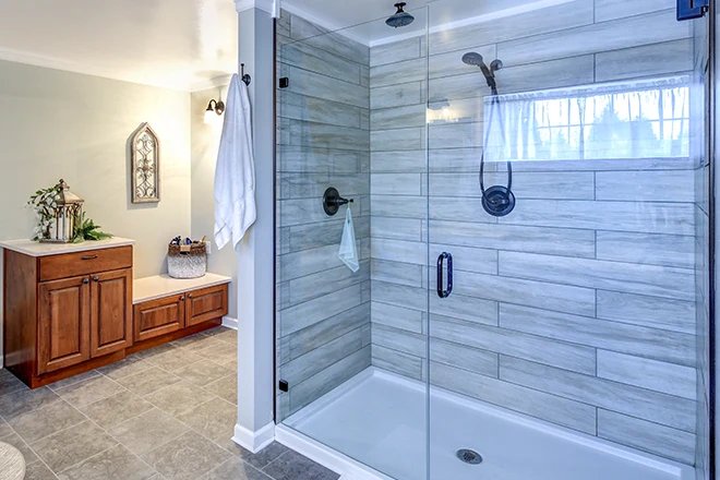 A modern walk-in shower with glass walls and stone tiles in a bathroom.