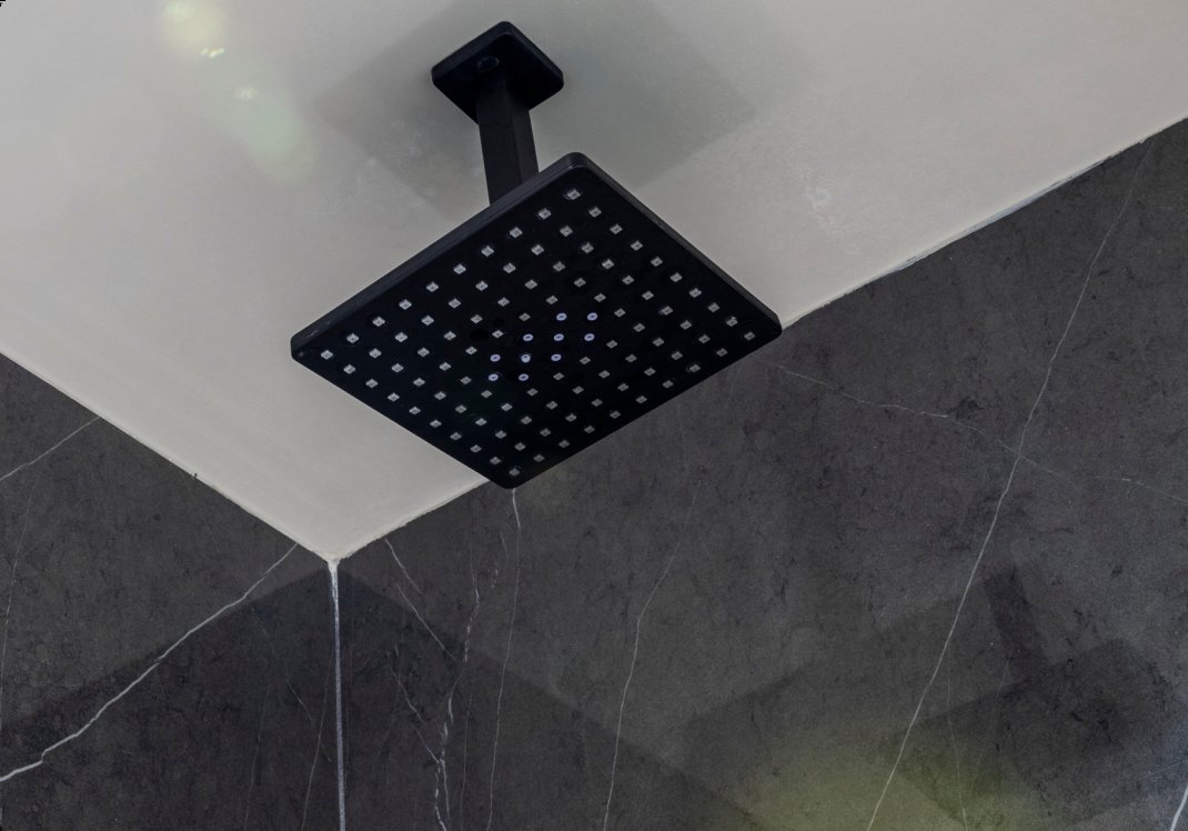 A massage shower head demonstrating a rhythmic pulsing water spray pattern.