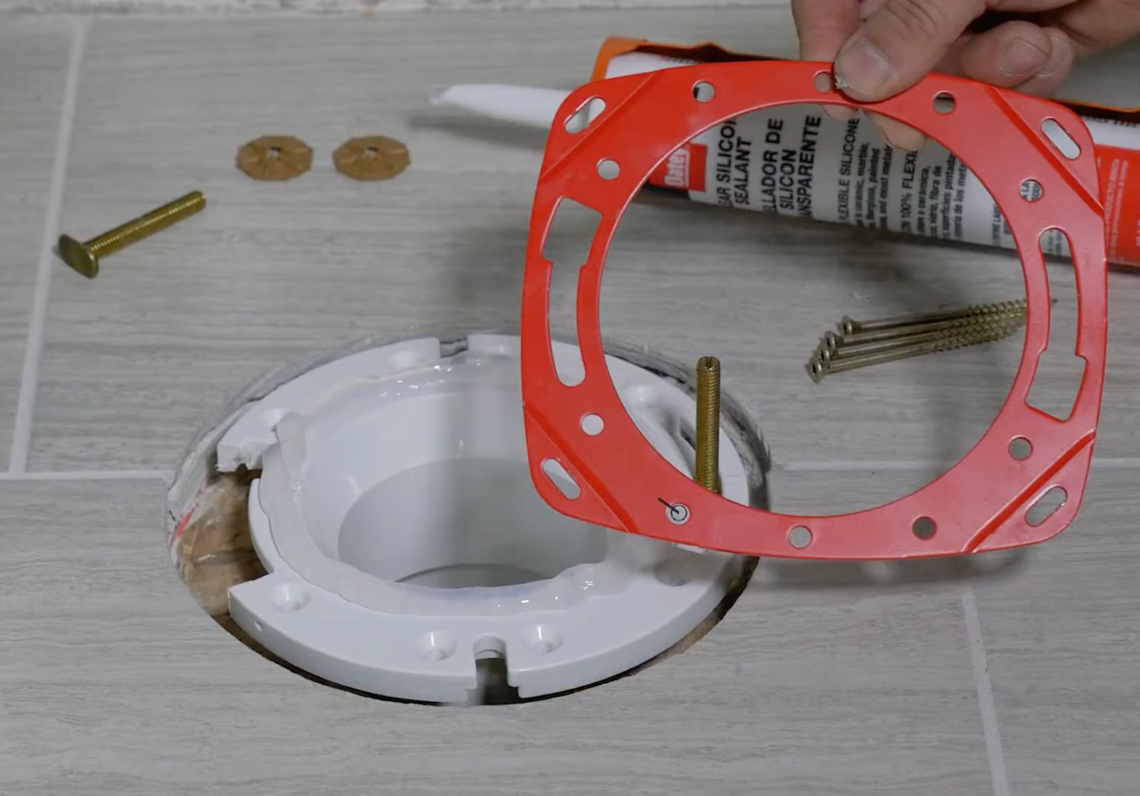 Hands checking for instability in a toilet base to identify a broken flange.