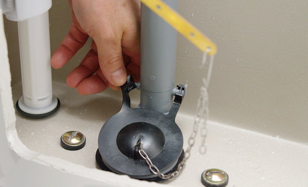A replacement toilet flapper and basic tools on a clean bathroom towel.