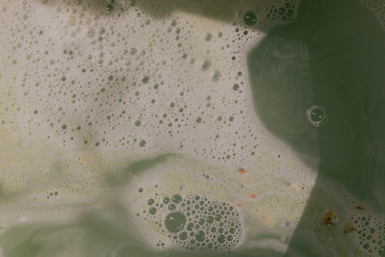 A person carefully testing the water temperature on their wrist before showering.