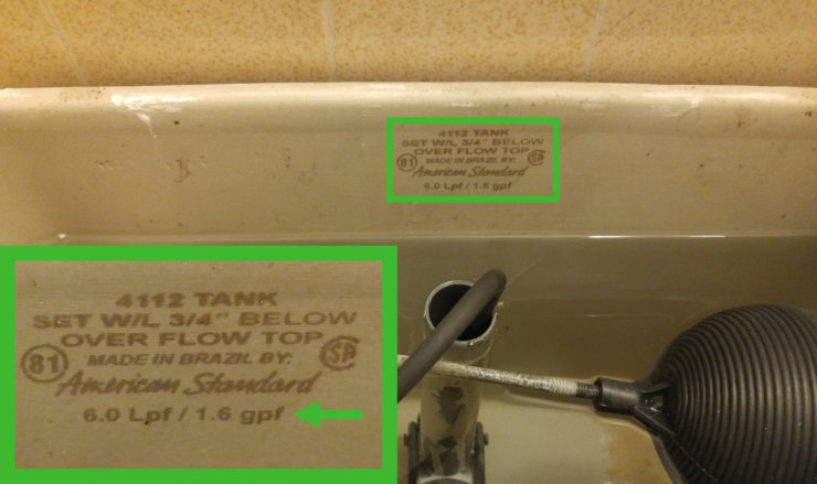A plastic water bottle sits inside a toilet tank next to a leaking flapper valve.