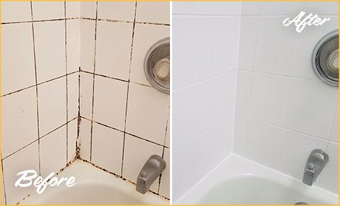 A pair of hands using a tool to remove old shower tile grout.