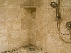 A clean, modern travertine shower wall showing natural stone patterns and pristine grout lines.
