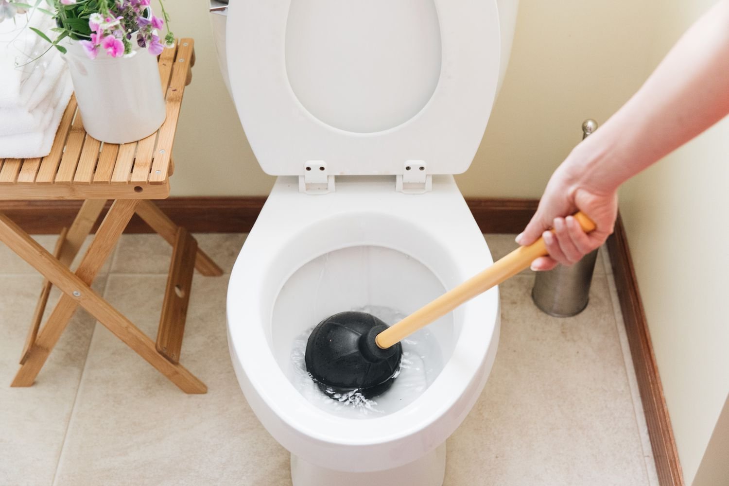 A plumber using a toilet auger to clear a stubborn drain blockage.
