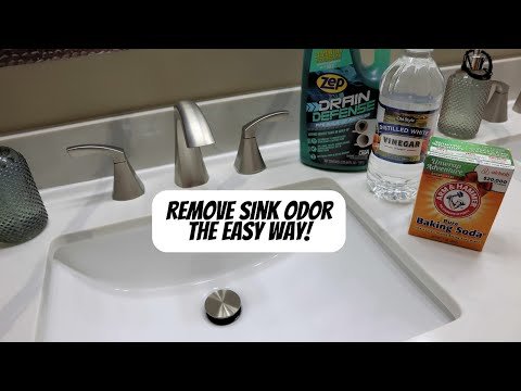 Hands unscrewing a P-trap pipe under a bathroom sink to clean the drain.