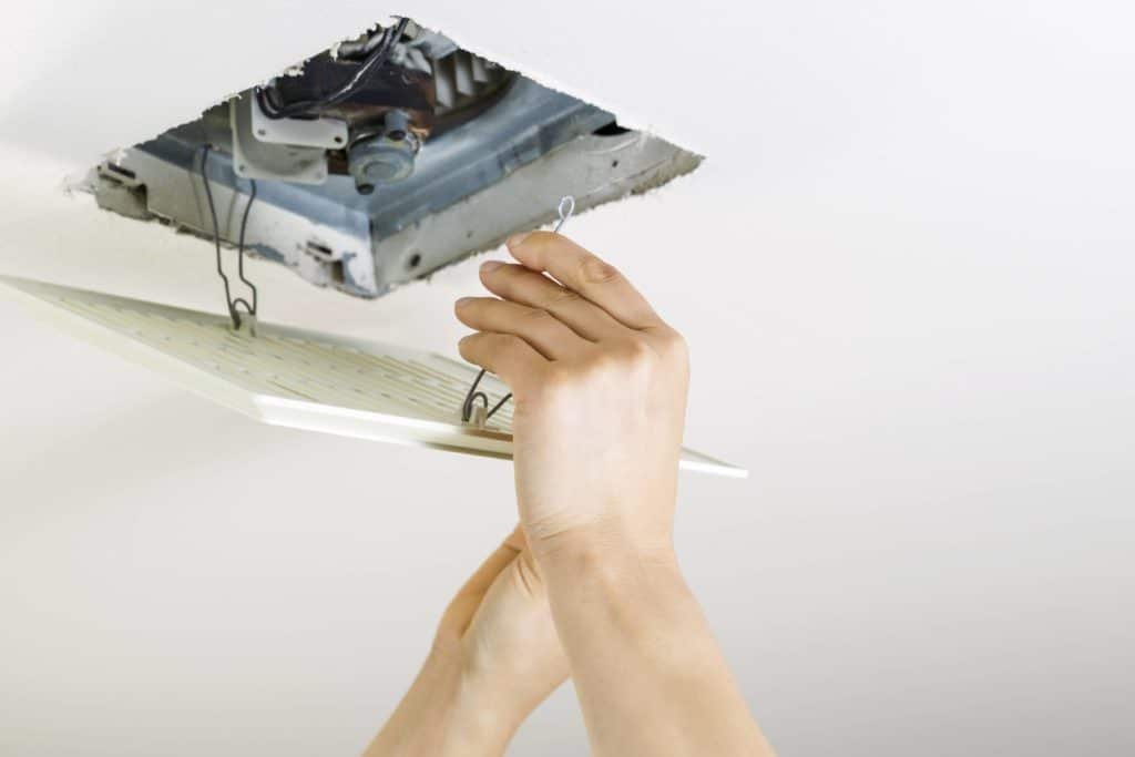 Essential tools for installing a bathroom exhaust fan arranged on a towel.