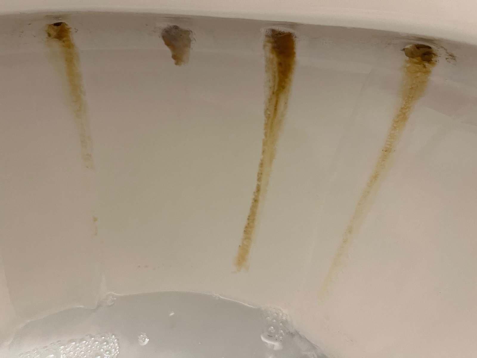 Essential cleaning supplies for removing yellow toilet stains laid out on tile.