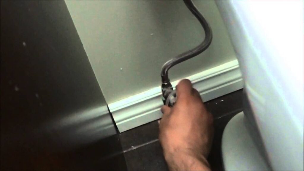 A clean bathroom showing the toilet and the essential water shutoff valve.