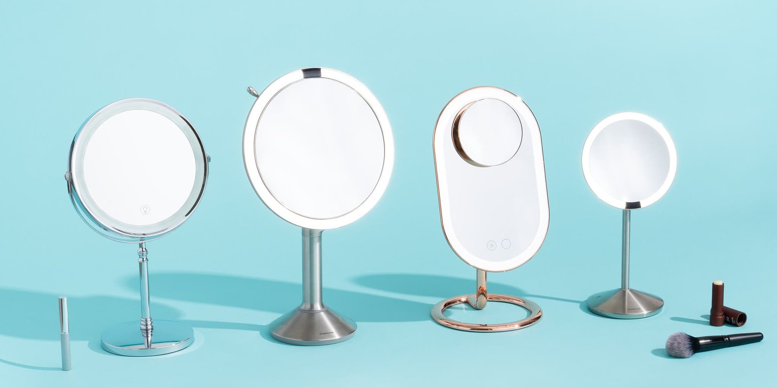 A collection of makeup mirror types arranged on a vanity for comparative viewing.