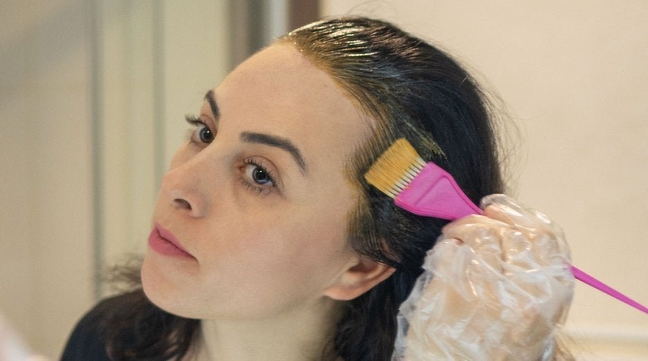 A person pouring hair dye remover shampoo into a bowl for color correction.