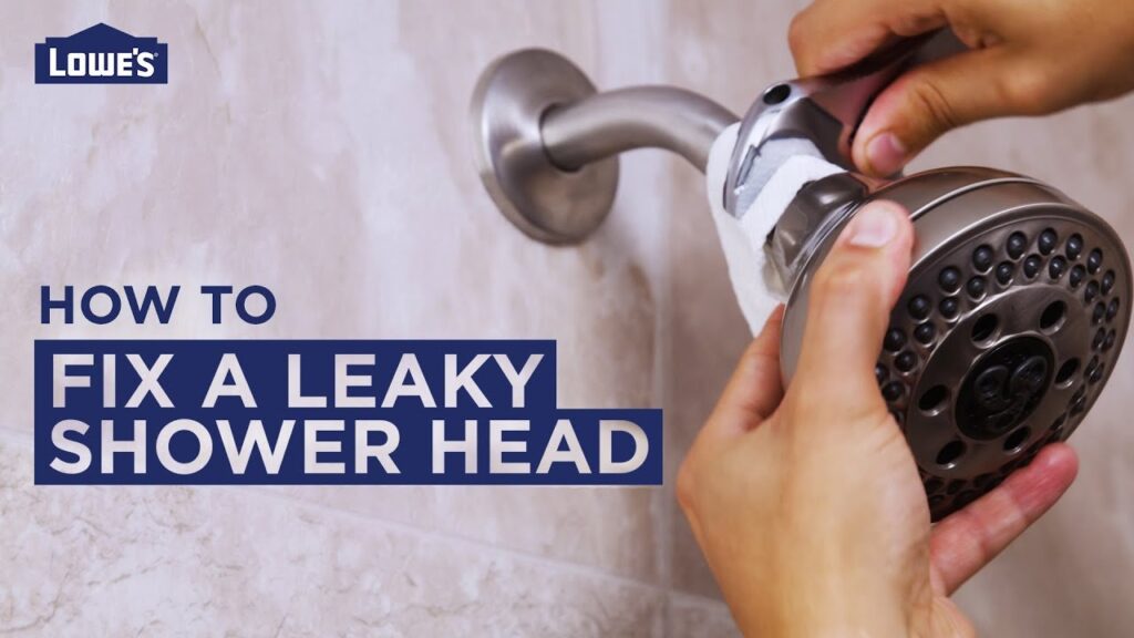 A leaking shower head connection dripping water in a modern tiled bathroom.
