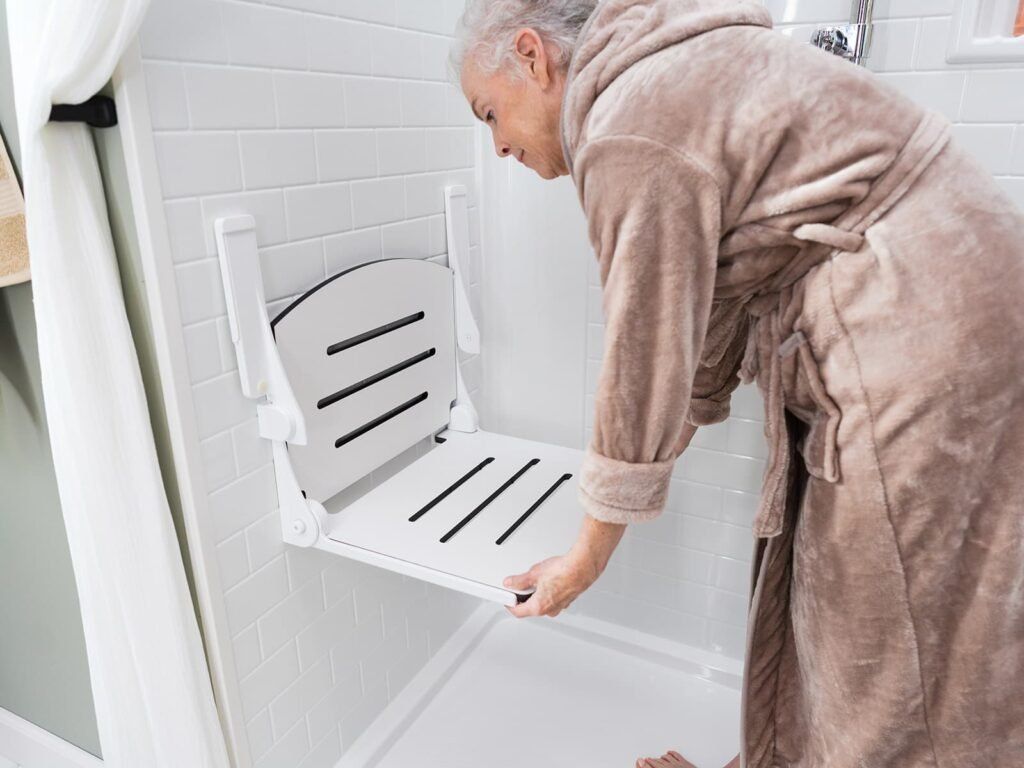 An elderly person using a fold-down shower seat for support while bathing.