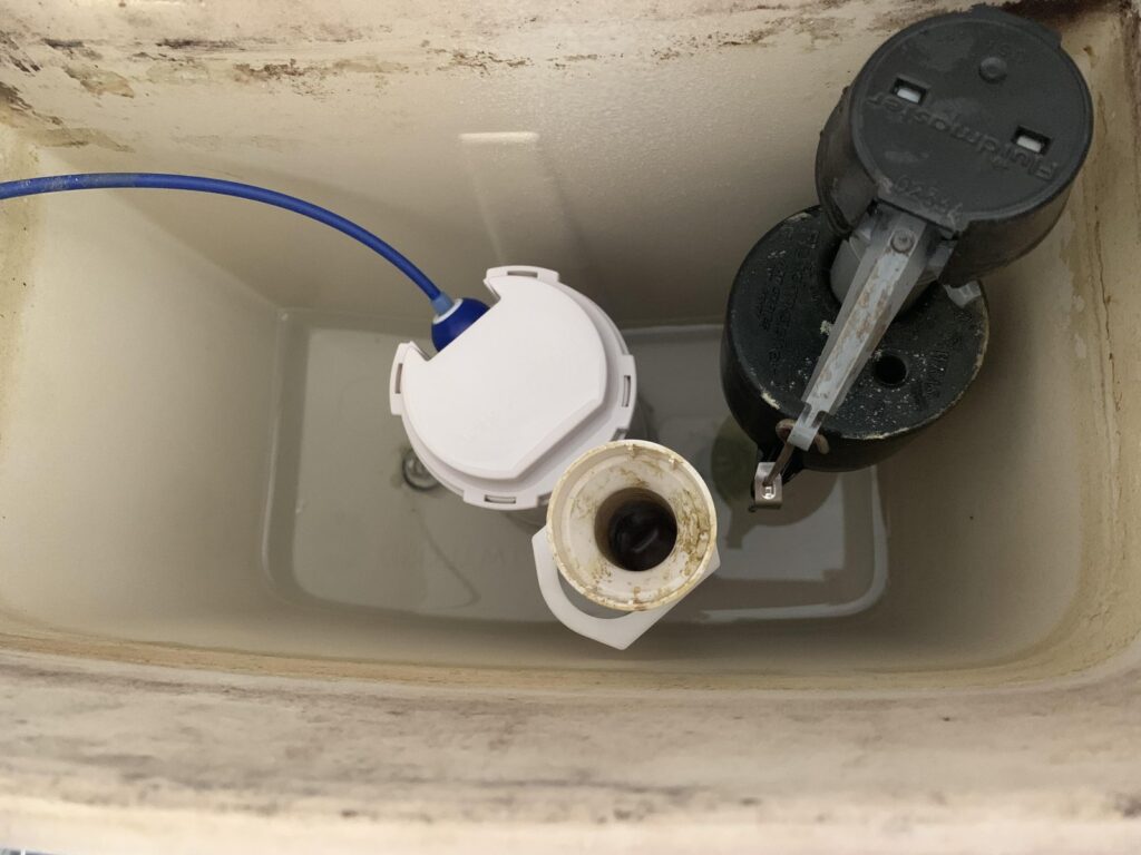 An open toilet tank showing the internal fill valve and float mechanism.