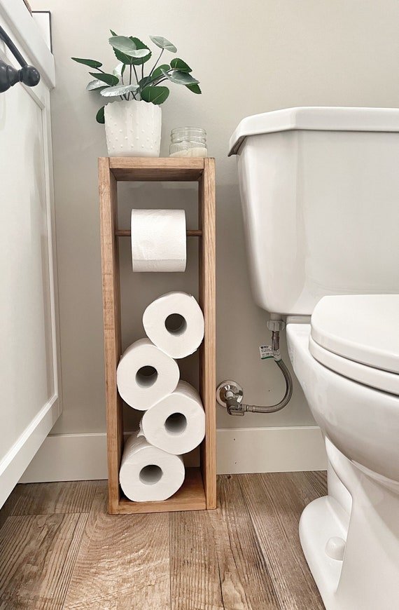 Tightening the set screw on a toilet paper holder to fix a sagging shelf.