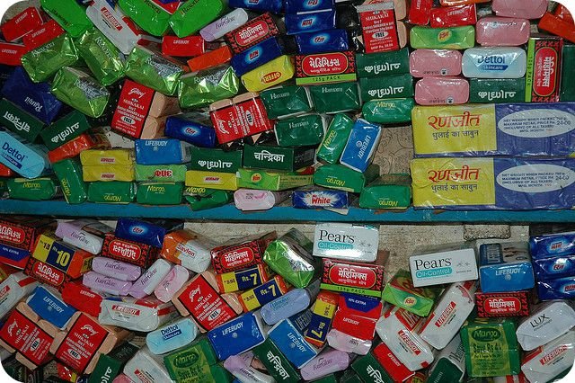 An assortment of soap bars displayed on a wooden shelf in a bathroom.