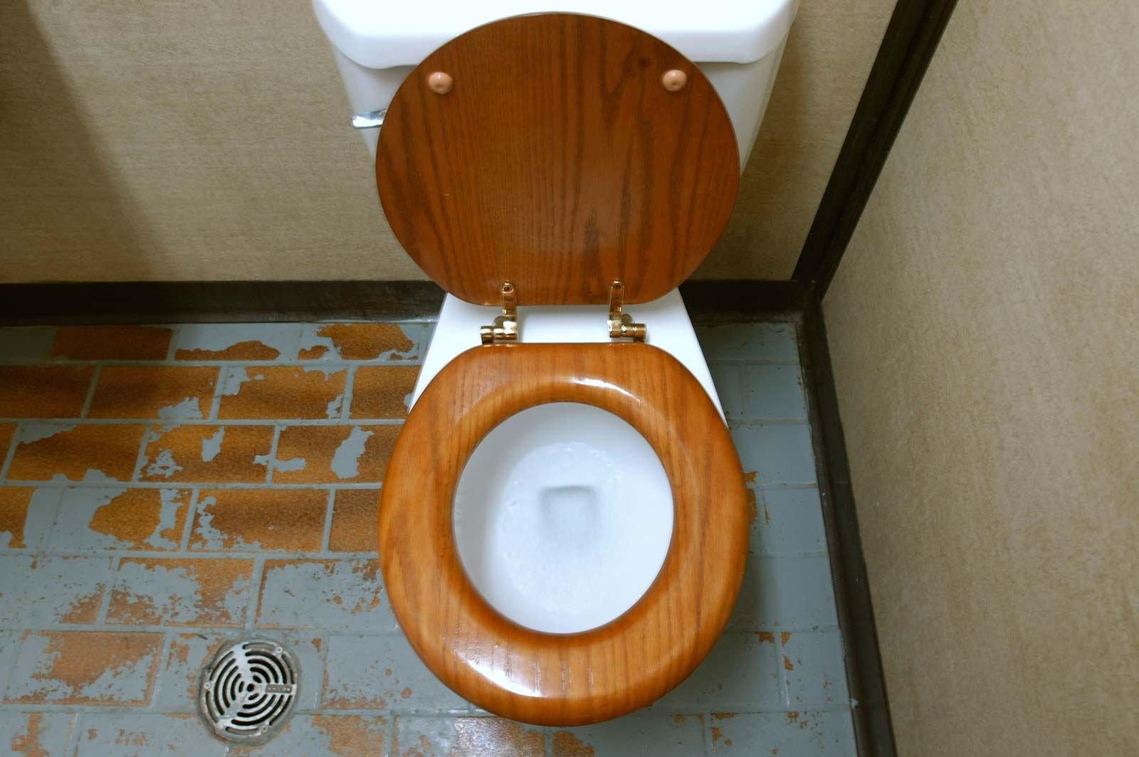 A close-up view of a bathroom floor with red tape applied around a toilet.