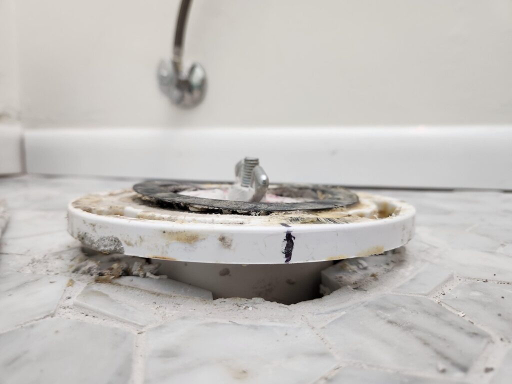 A gap exists between the toilet base and floor due to a high flange.