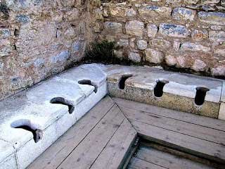 Ancient stone drainage channels and clay pipes discovered at an archaeological excavation site.
